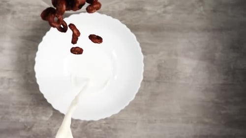 Pouring Chocolate Cereal and Milk Into a Bowl