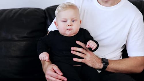 Cute Infant Sitting on Adult's Lap Indoors