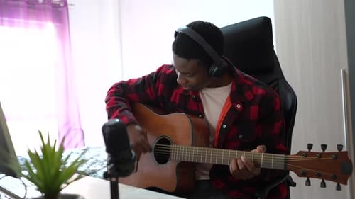 Man Playing Guitar in Front of Microphone
