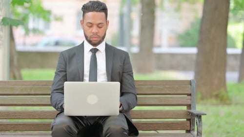 Businessman Working on Laptop while Sitting Outdoor on Bench