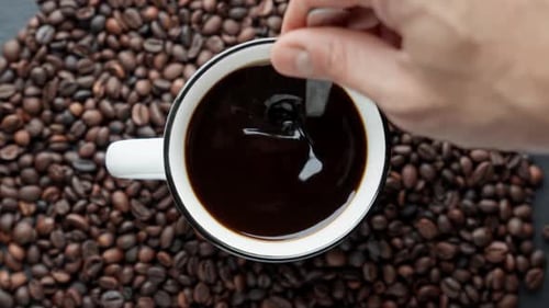 Hand Stirring Coffee with Beans Overhead
