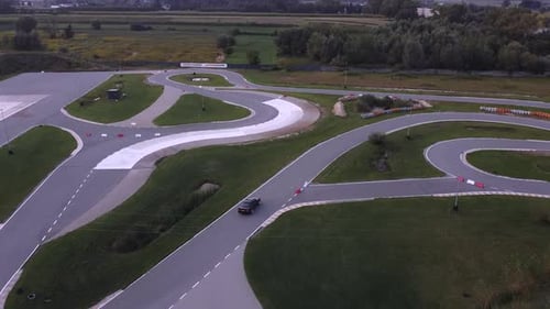 Sport car driving on real racetrack; aerial shot of moving black sport car on real racetrack