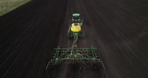 Tractor with a Seeder Rides Across the Field Aerial View