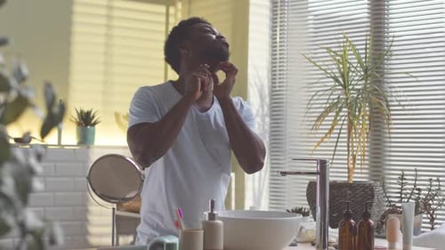 Man Shaving Beard in Bright Bathroom