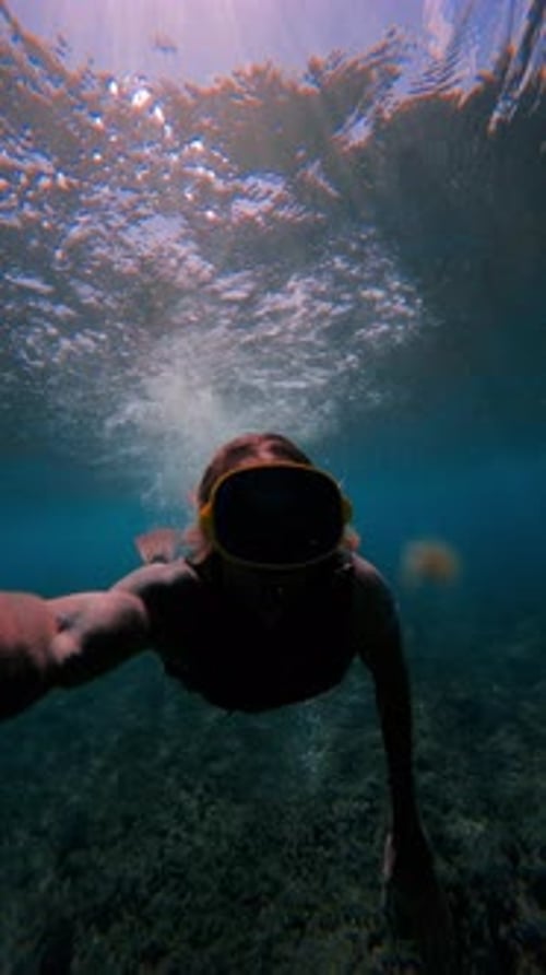 Vertical Shot Of Athletic Swimmer Diving Deep Into Blue Ocean Turbulence Foam