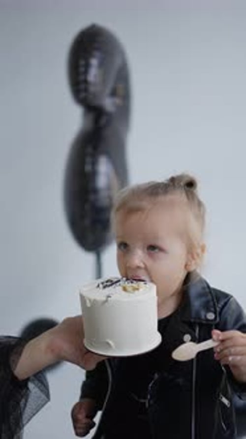 Toddler Eats Birthday Cake at Party Indoors