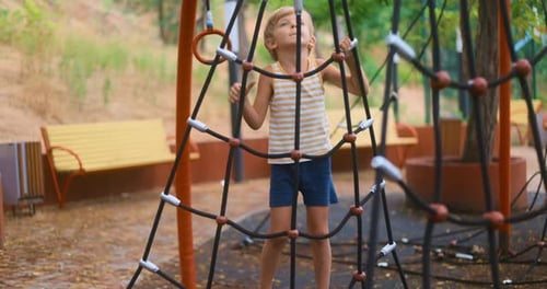 Child Climbing Rope Structure in Outdoor Playground