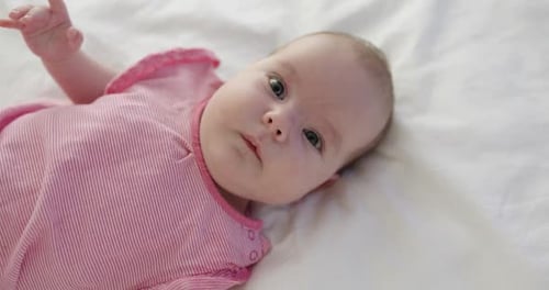 Adorable Infant Lying on White Blanket at Home