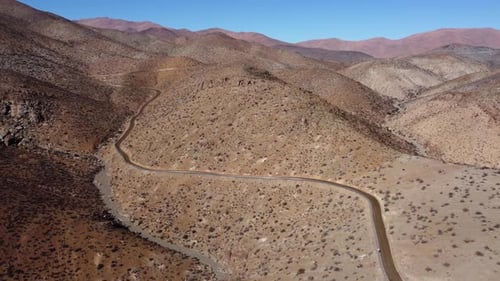 Rough arid hilly landscape aerial: Serpentine dirt road winds through