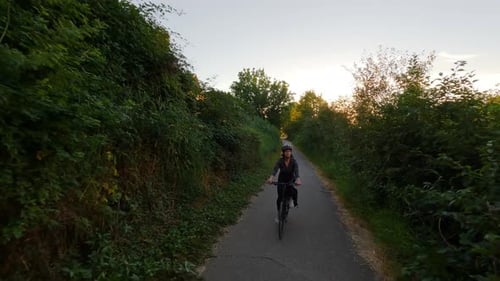 Adventure Woman Bike Riding on a Bicycle Trail Surrounded By Green Trees