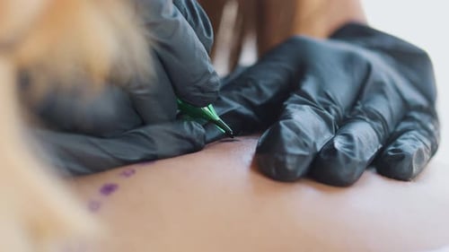 Tattooing Process Close Up Tattoo Machine Studio Künstlerin, schwarze Handschuhe