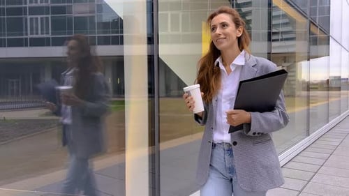 Businesswoman Walks with Coffee Outside Office Building