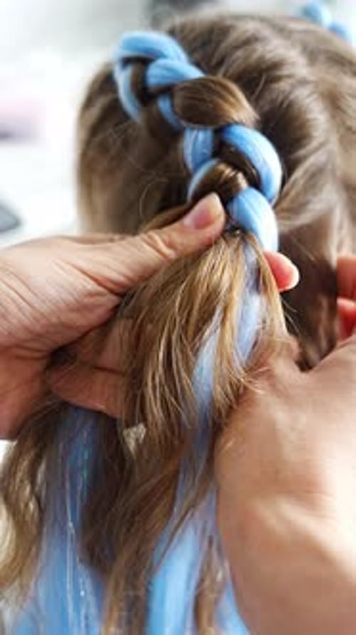 Mãe trançando extensões de cabelo sintéticas coloridas em um penteado de menina em casa Creative