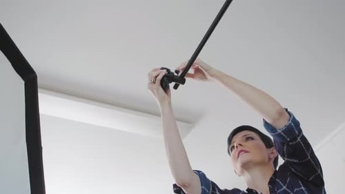 Photographer Adjusts A C-Stand In Her Studio. Shot On A Canon C200 In 4k.