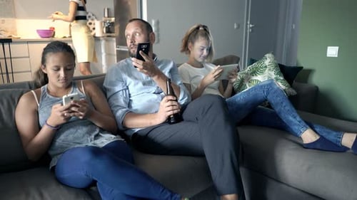 Family Relaxing on Sofa Using Phones and Tablet