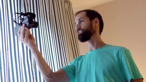 Man Holding Camera Indoors and Talking