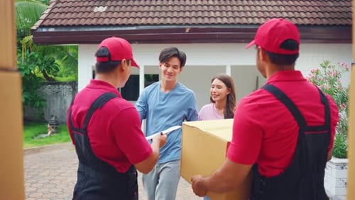 Young delivery man delivering package to couple customer at home.