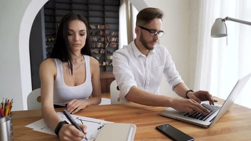 Two young entrepreneurs collaborating on a new business project in trendy loft workspace