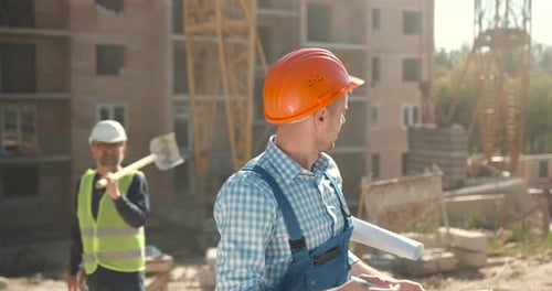 Construction Worker Reviews Plans on Building Site