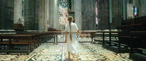 Femme visitant une ancienne église. Fille qui cherche Dieu dans le temple. Un paroissien se promène le long des bancs.