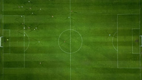 Vista aérea de un campo de fútbol en acción con jugadores corriendo, pasando y marcando goles