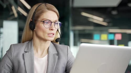 Business Woman Using Laptop and Headset in Office
