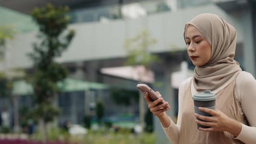 Portrait of Muslim Businesswoman Holds Smartphone and Coffee Cup Outside Office