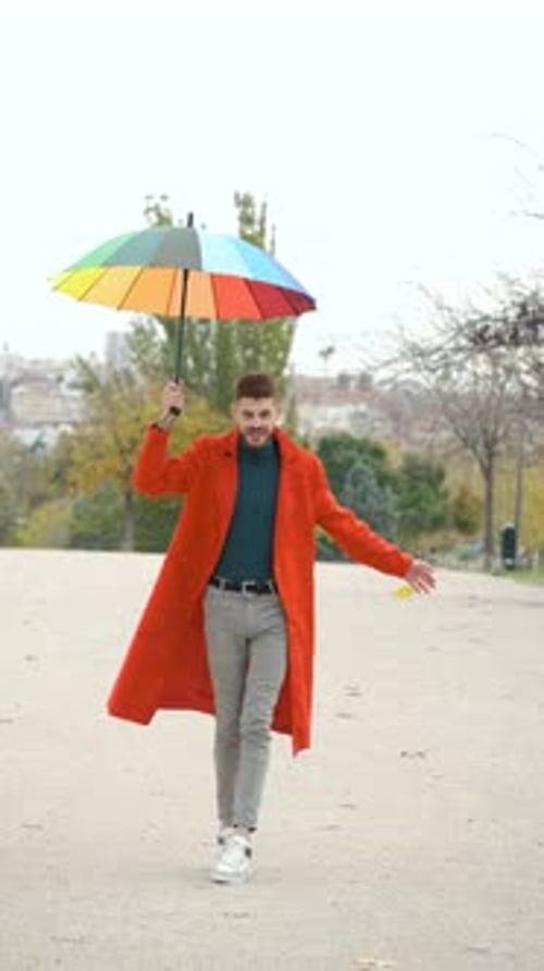 Smiling Man with Umbrella Walks Through Autumn Park