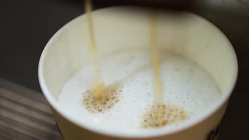 Pouring Espresso into Frothy White Cup Close Up