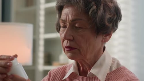 Senior Woman Examining Pill Bottle Indoors