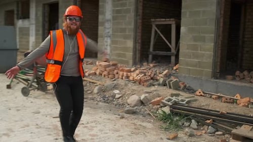 Um trabalhador da construção civil sorridente dança e pula, se droga, sonha e aproveita a obra concluída