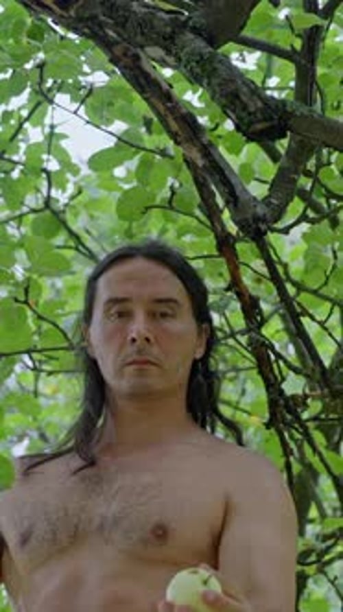 Um homem sem camisa posa com confiança entre a exuberante folhagem verde que personifica uma profunda conexão com a natureza