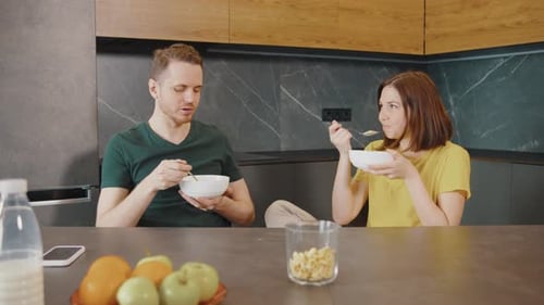 Couple Eating Cereal and Talking in Kitchen