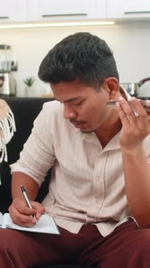 Un Indien sur haut-parleur passe un appel professionnel et écrit des notes claires dans une conversation axée sur un bloc-notes
