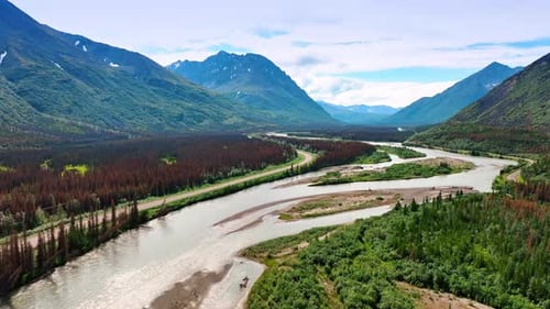 Beautiful shallow river flowing by the picturesque valley. Brown dry pine tree woods grow around.