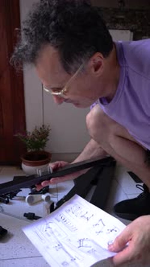 Homme concentré regardant les instructions du manuel lors de l'assemblage des meubles