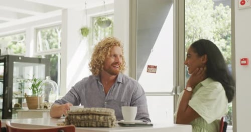 Happy diverse couple drinking coffee and talking at a table in cafe