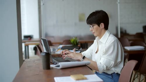 Attractive Mature Businesswoman Working on Laptop in Office or Coworking