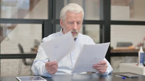 Senior Man Reviews Documents, Reacts with Joy