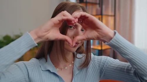 Woman Makes Heart Symbol with Hands Indoors