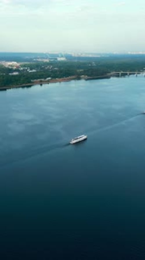 Passenger Ferry Navigating River at Sunrise Near City Coastline Clip