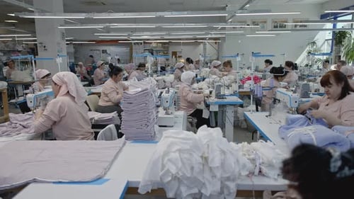 Herstellung von Kleidung in der großen Fabrik Media Factory Mitarbeiter nähen Kleidung an den Tischen
