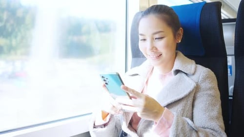 Woman Using Phone on Train During the Day