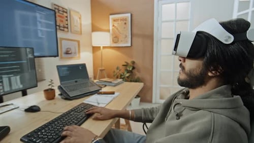 Programmer in VR Goggles Working on Computer Code from Home