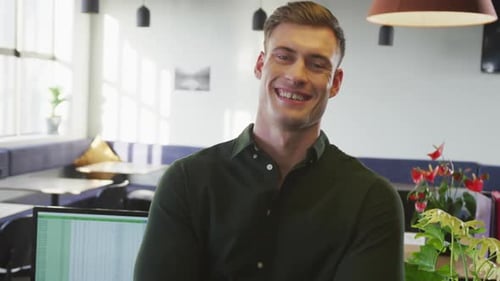 Portrait of happy caucasian businessman looking at camera at office