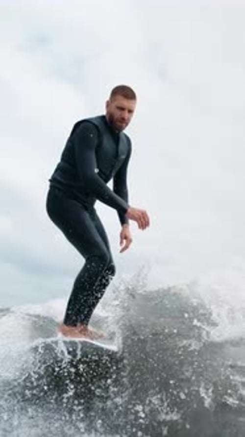 Man in Wetsuit Rides Surfboard on Ocean Wave
