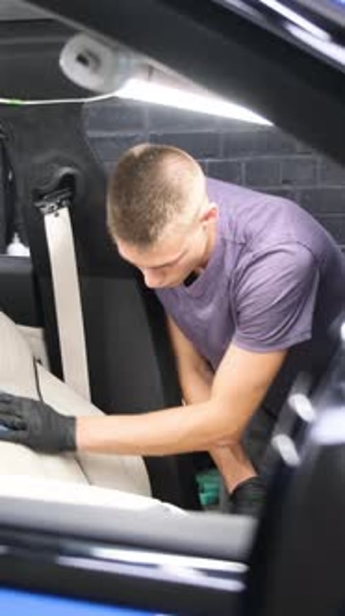 A Man Does Dry Cleaning of the Car Interior Vacuums the Car Interior Vertical Video