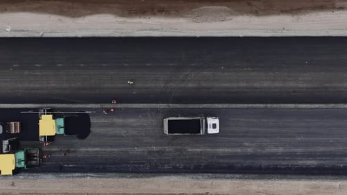 Dump Truck and Asphalt Pavers with Builders on Highway