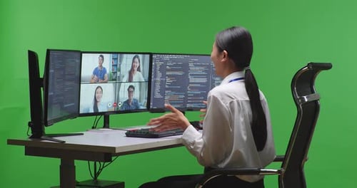 Entwicklerin hat Video, während sie Code mit mehreren Computerbildschirmen im Green Screen Studio schreibt