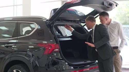 A Young Man is Talking to a Car Salesman A Guycustomer Buys a Vehicle in the Showroom